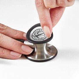 Vingers verwijderen het instelbare membraan van de kelk van een 3M Littmann Classic III Stethoscoop.